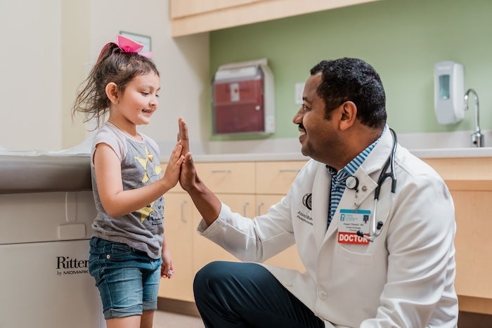 A doctor high fiving a little girl