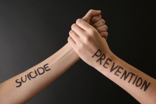 Two hands, one labeled suicide and one labeled prevention, clasped together