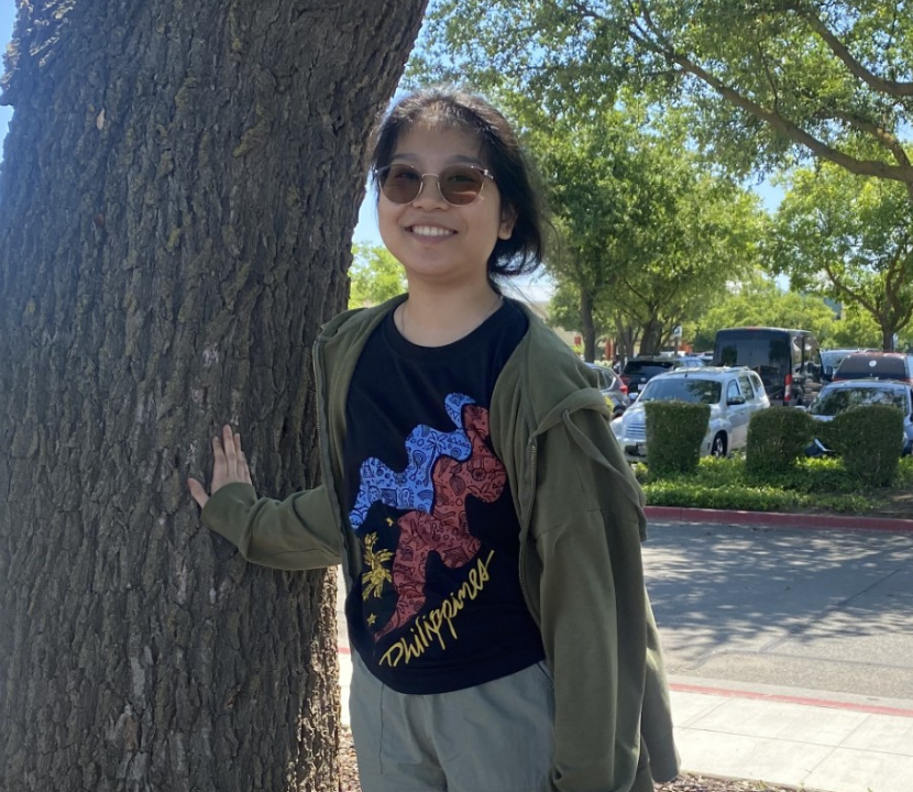 Faith smiles as she poses near a tree