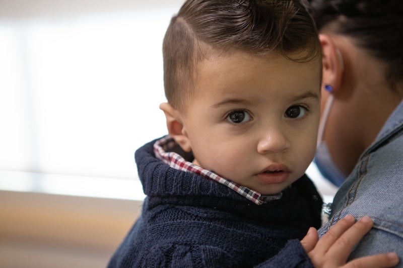 A very small child being held as he looks into the camera