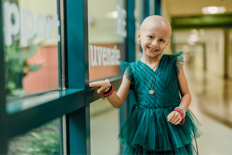 A young girl smiles by a window
