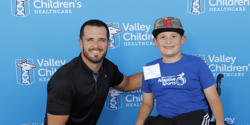 Luke smiles with pro quarterback Derek Carr
