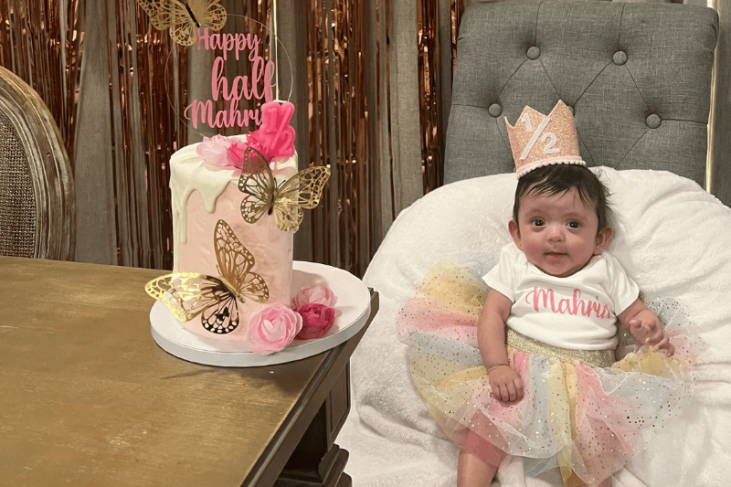 A baby girl smiles next to her birthday cake