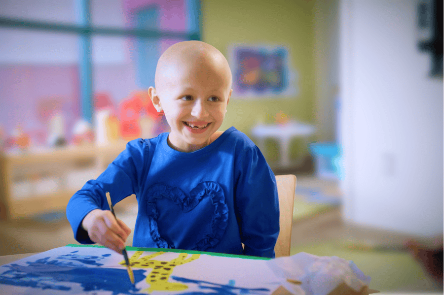 A young girl smiles as she paints a picture