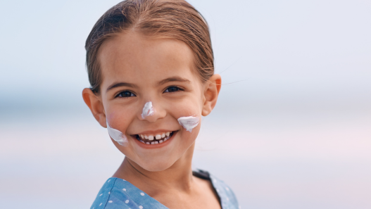Child smiling with sunscreen on their face