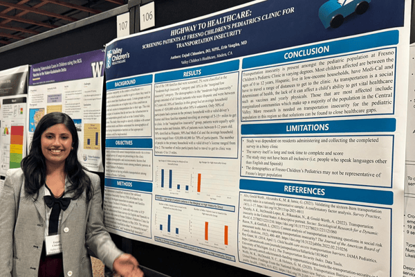Pediatric resident in front of a research poster at a conference